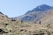 A group of diverse travelers enjoying a scenic landscape with mountains and a blue sky.