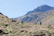 A serene mountain landscape with a small group hiking under a clear sky.