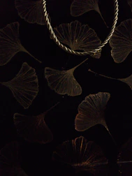 Elegant curved dowsing rods resting on a light fabric with subtle ginkgo leaf patterns.