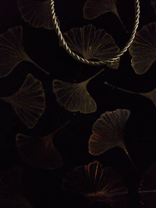 Elegant curved dowsing rods resting on a light fabric with subtle ginkgo leaf patterns.