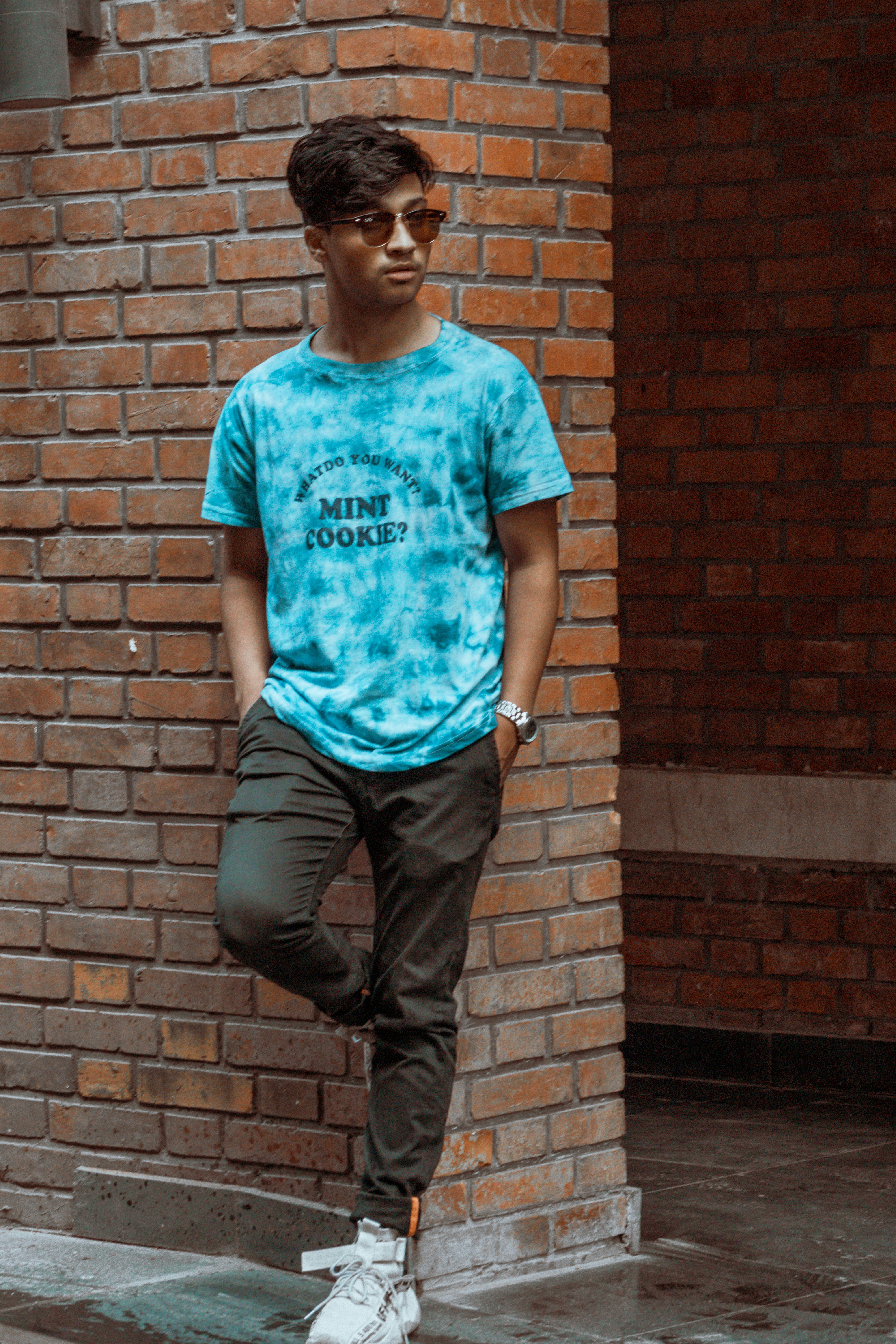 a man standing in front of a brick wall