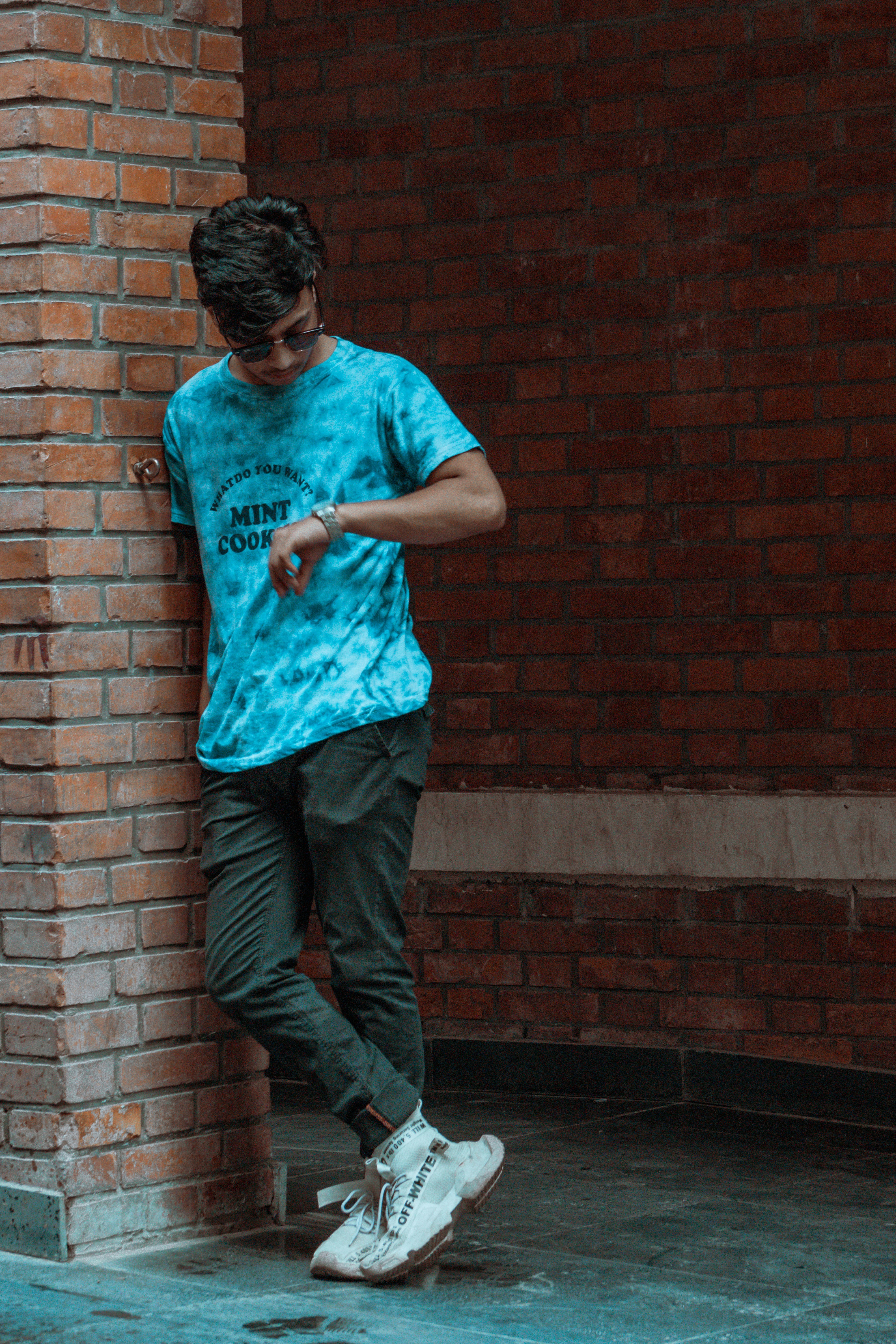 a man standing in front of a brick wall