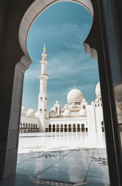 A serene view of Noorani mosque's elegant dome and minaret against a clear blue sky.