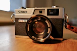 Close-up of a classic UBM Canon camera resting on a wooden table.