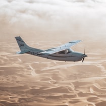 a small airplane flying over sand