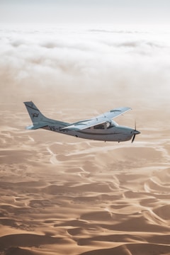 a small airplane flying over sand