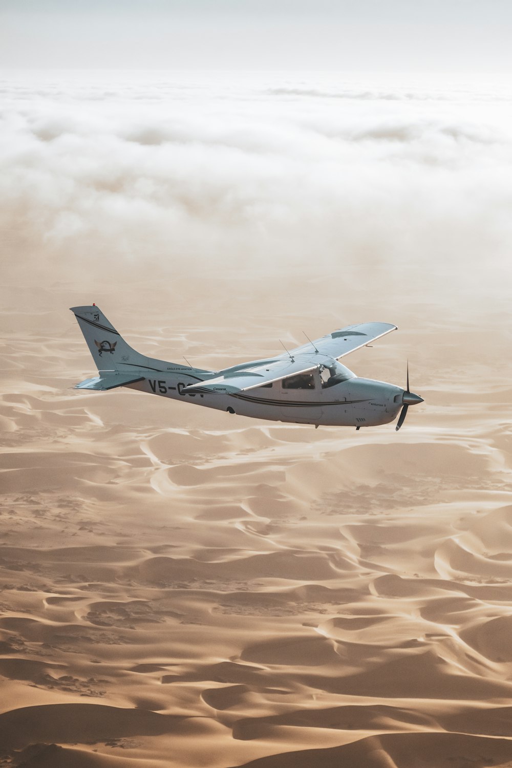 a small airplane flying over sand