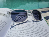 Trendy sunglasses resting on a vintage book with natural sunlight.
