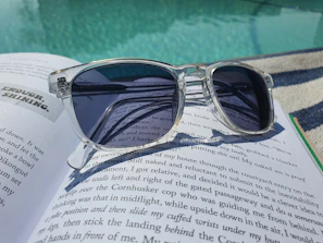 Trendy sunglasses resting on a vintage book with natural sunlight.