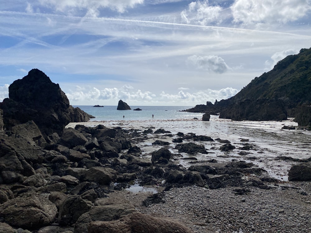 a rocky beach with a body of water in the background