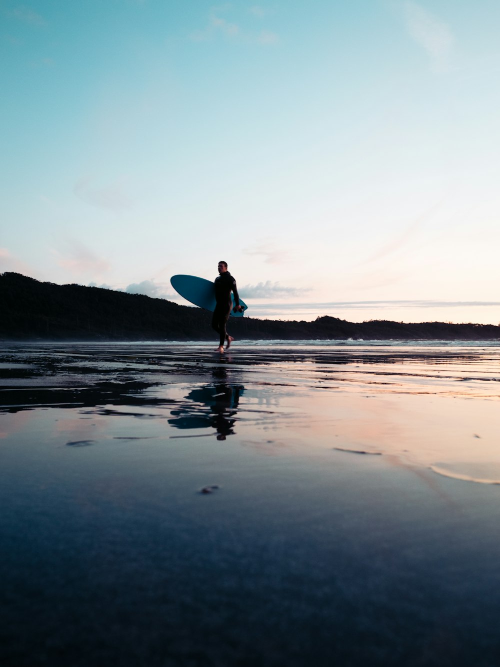 a man carrying a surfboard on a beach