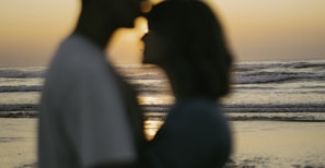 Silhouetted couple sharing a quiet moment at sunset by the water