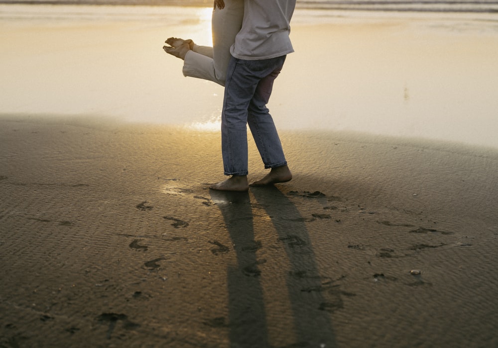 a person holding a child's hand on a beach