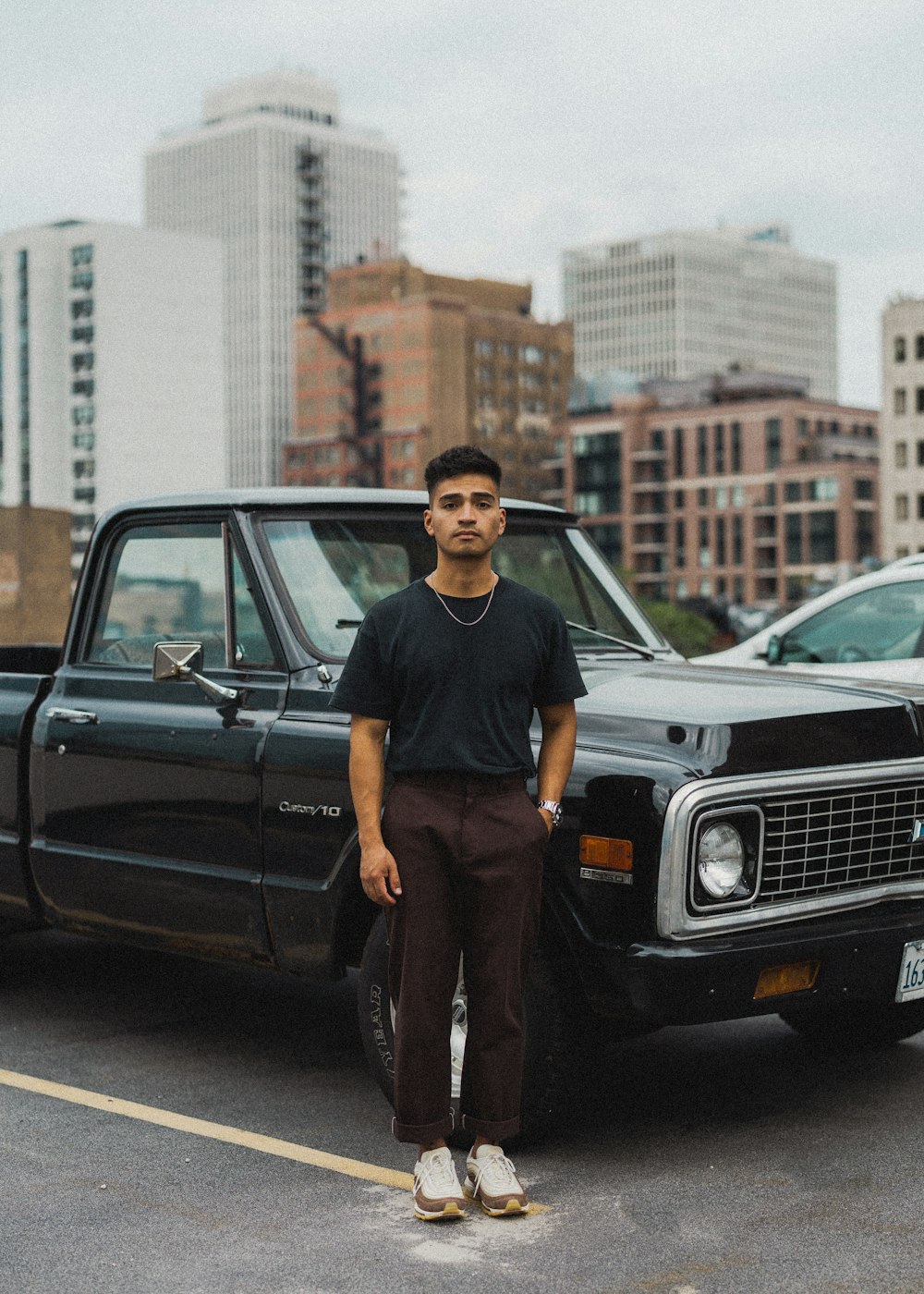 a man standing in front of a car in a parking lot