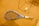 A tennis racket with a blue frame lies on a brown, textured surface, alongside a tennis ball. There are metal frame structures casting shadows across the scene, suggesting an indoor setting.