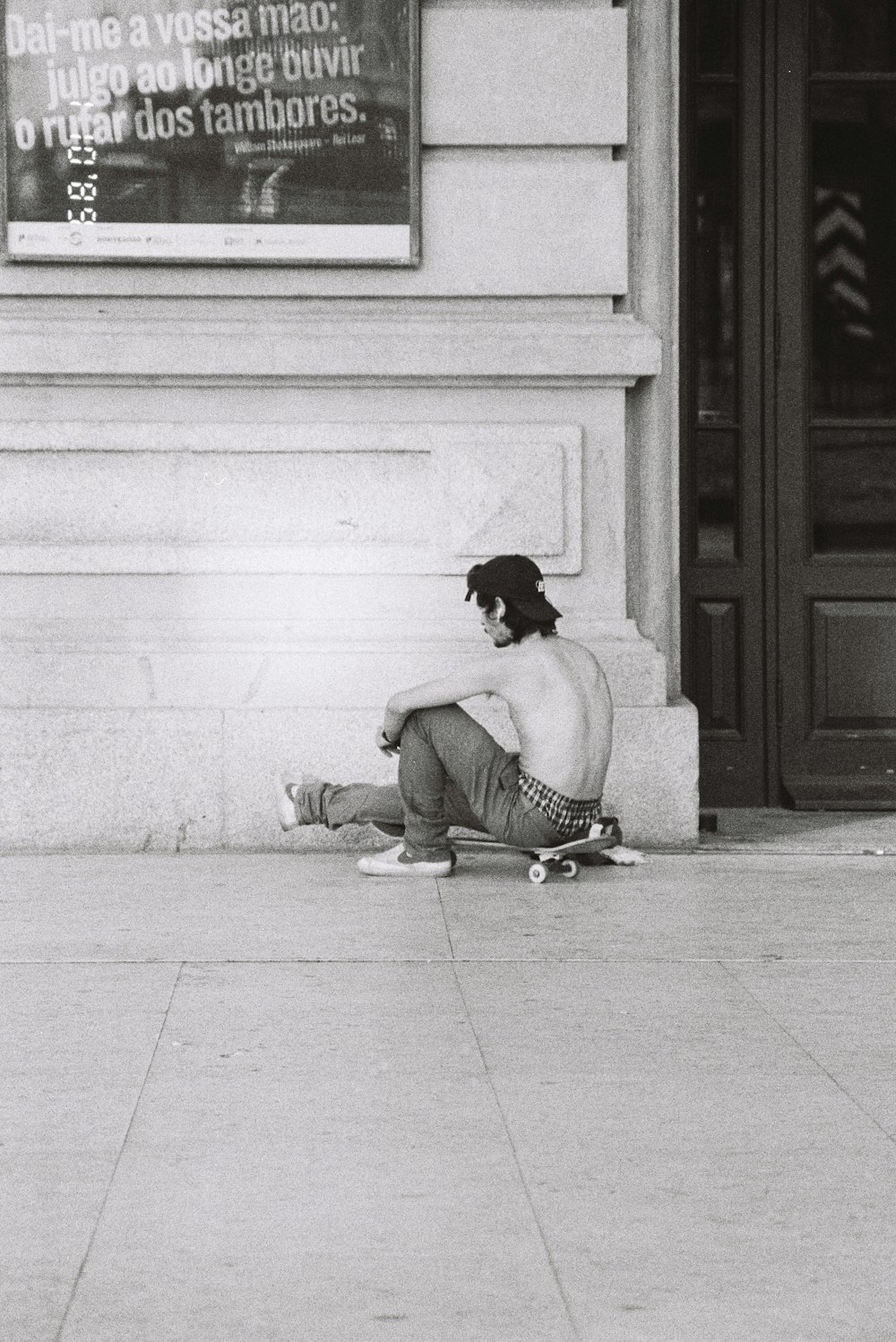 a man sitting on a sidewalk with a skateboard