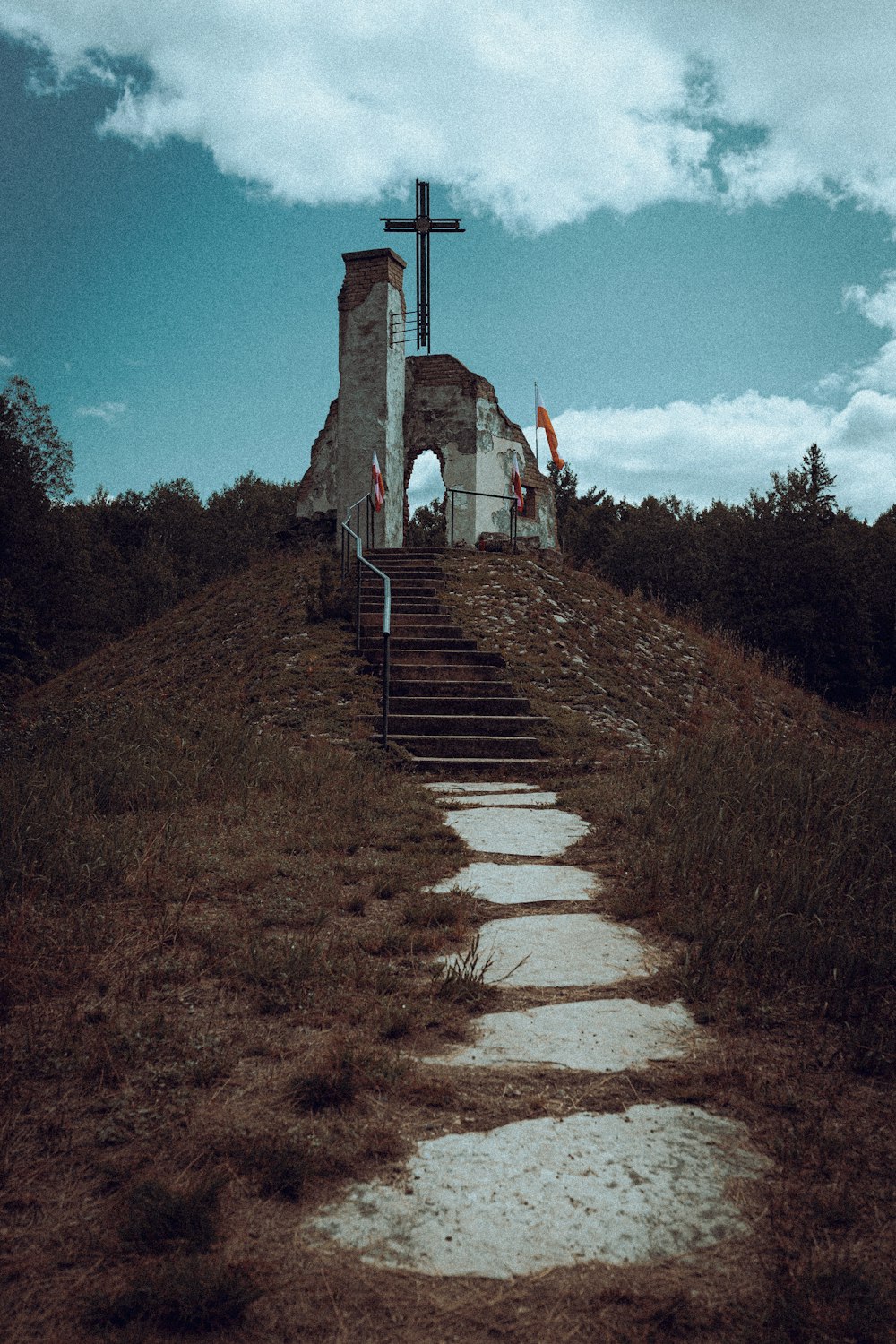 a person walking up a staircase leading up to a cross on a hill