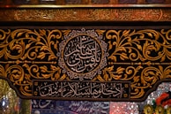 Intricate Arabic calligraphy is surrounded by ornate gold floral patterns on a dark background. The writing includes both circular and rectangular frames. The decorative style is rich and detailed, reflecting traditional artistry.