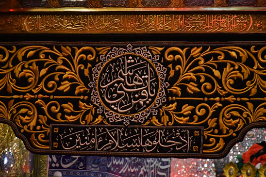 Close-up of a gold-finished CNC-cut Islamic calligraphy frame glowing softly against a cream parchment background.
