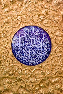 Close-up of a delicate thuluth calligraphy piece with gold ink on deep blue background