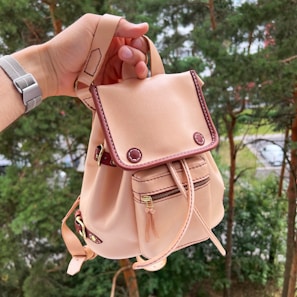 A mom’s backpack with a whimsical print lip balm holder attached, sunlight filtering through leaves.