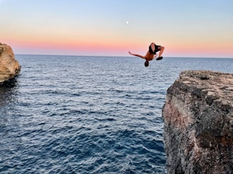 a person jumping off a cliff into the water