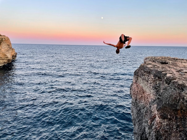 a person jumping off a cliff into the water