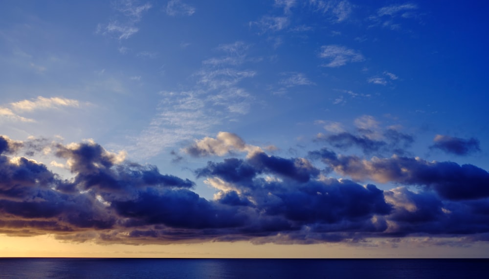 a body of water with clouds above it