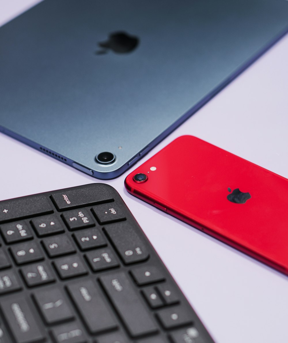 a red cell phone next to a black keyboard