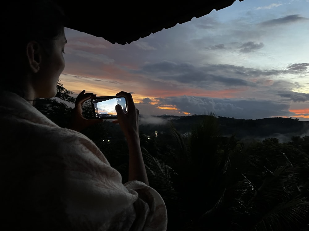 a person taking a picture of the sunset
