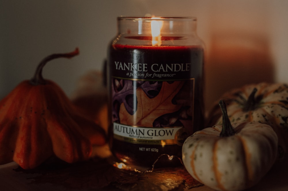 a jar of pumpkins next to a candle and a pumpkin