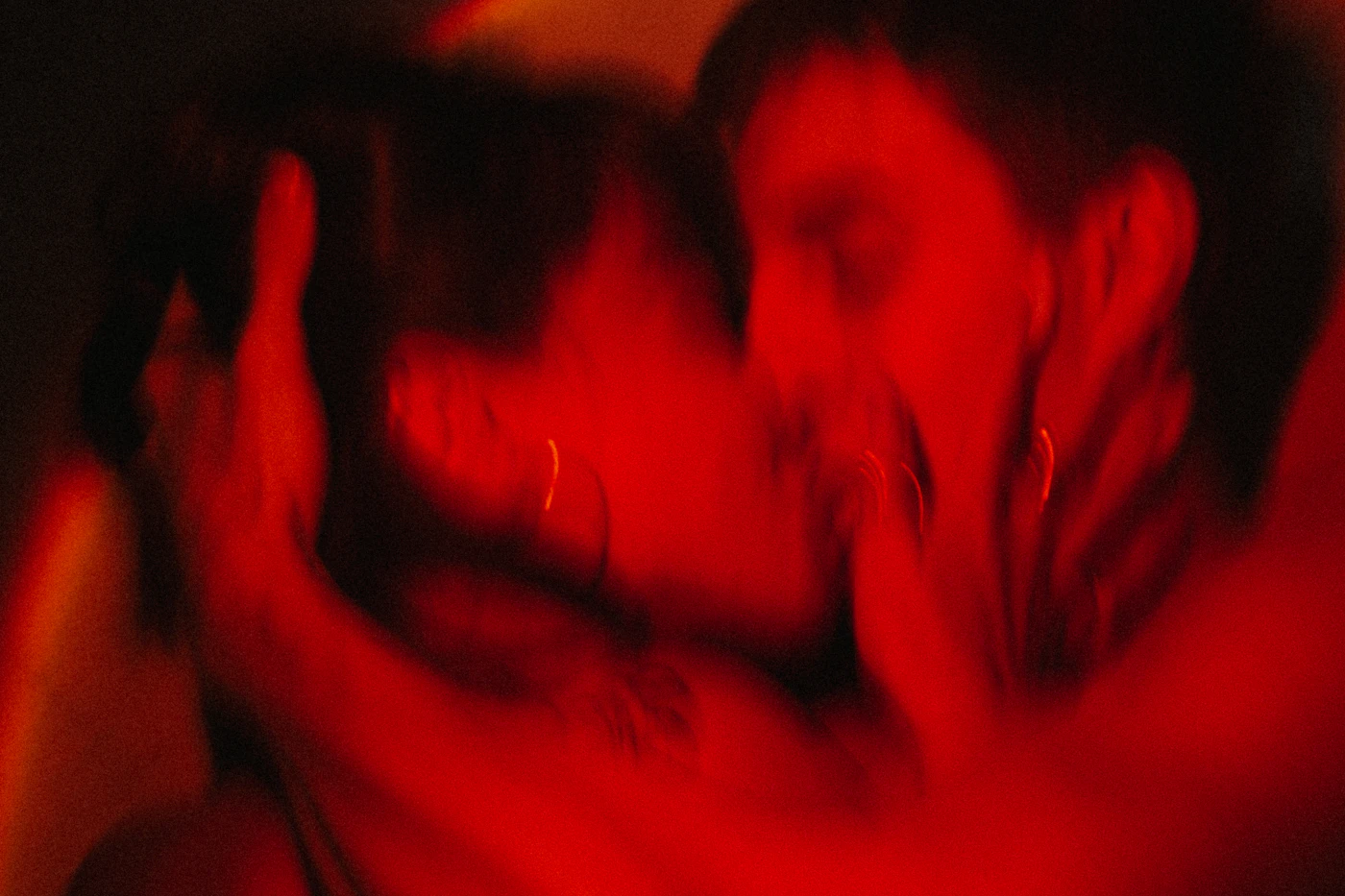 Two people rendered as soft silhouettes in red and black light