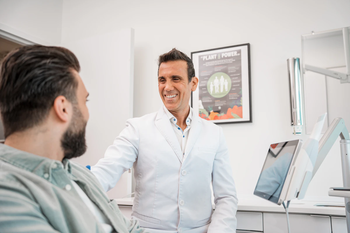 A dentist smiling while talking with a patient in a modern dental office