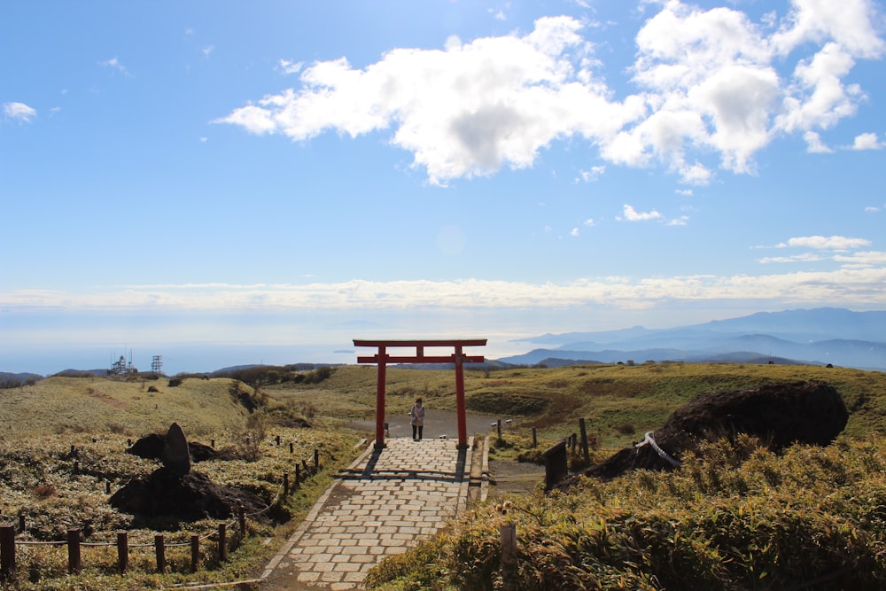 a person walking on a path in a grassy area with a large wooden structure in the distance