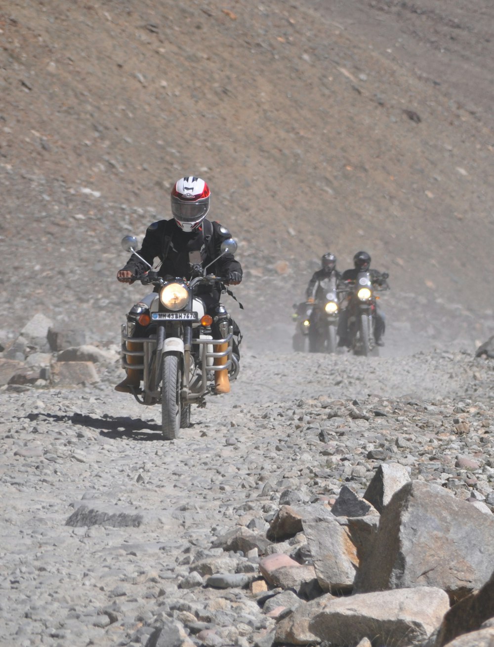 Eine Gruppe von Menschen, die Motorräder auf einem felsigen Gelände fahren