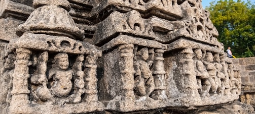 Intricately carved stone sculpture depicting human and animal figures, possibly part of an ancient temple or historical monument. The detailed carvings illustrate artistic and architectural styles, indicating cultural significance.