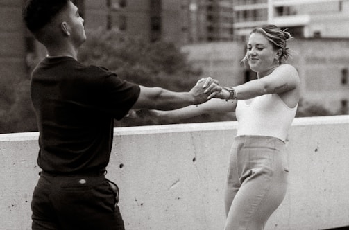 Black-and-white photo of a couple holding hands against a city night backdrop.
