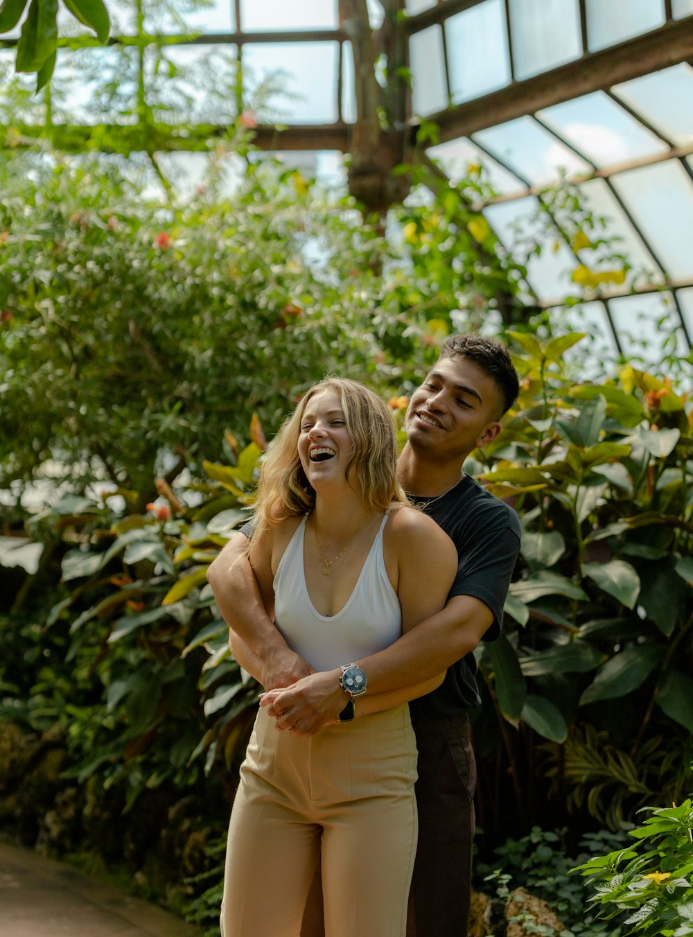 a man and woman standing together in front of a garden