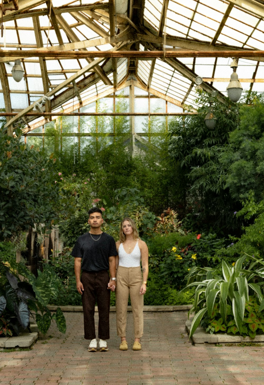 a man and woman standing under a covered area with plants and a structure