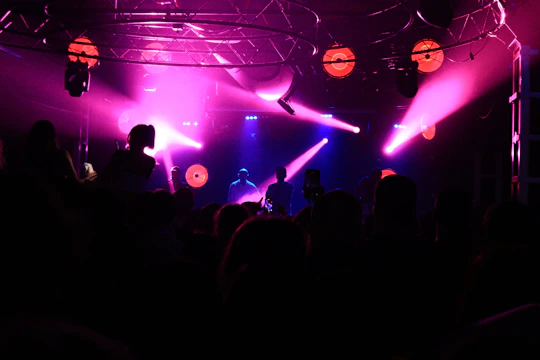 Crowd at a nighttime rock concert with vibrant red stage lights and energetic musicians.