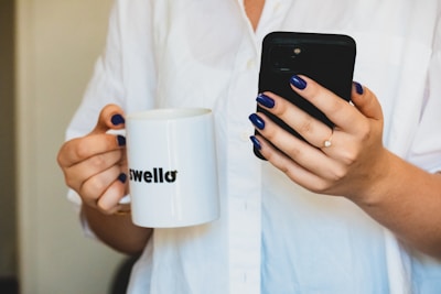 a man holding a phone and a cup of coffee