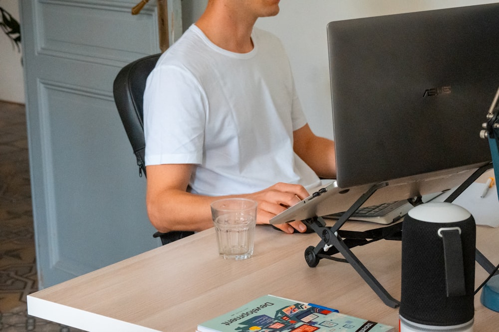 a man sitting at a desk with a computer and a glass of water