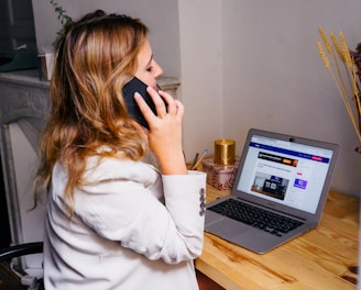 a woman sitting at a desk with a laptop and a phone