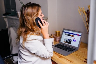 a woman sitting at a desk with a laptop and a phone