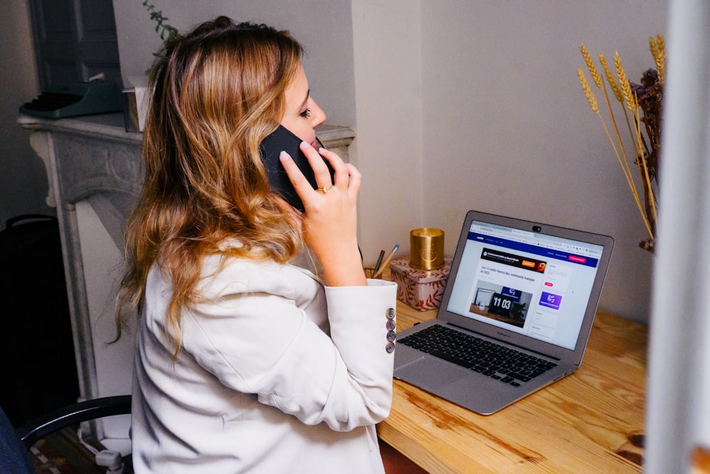 a woman sitting at a desk with a laptop and a phone