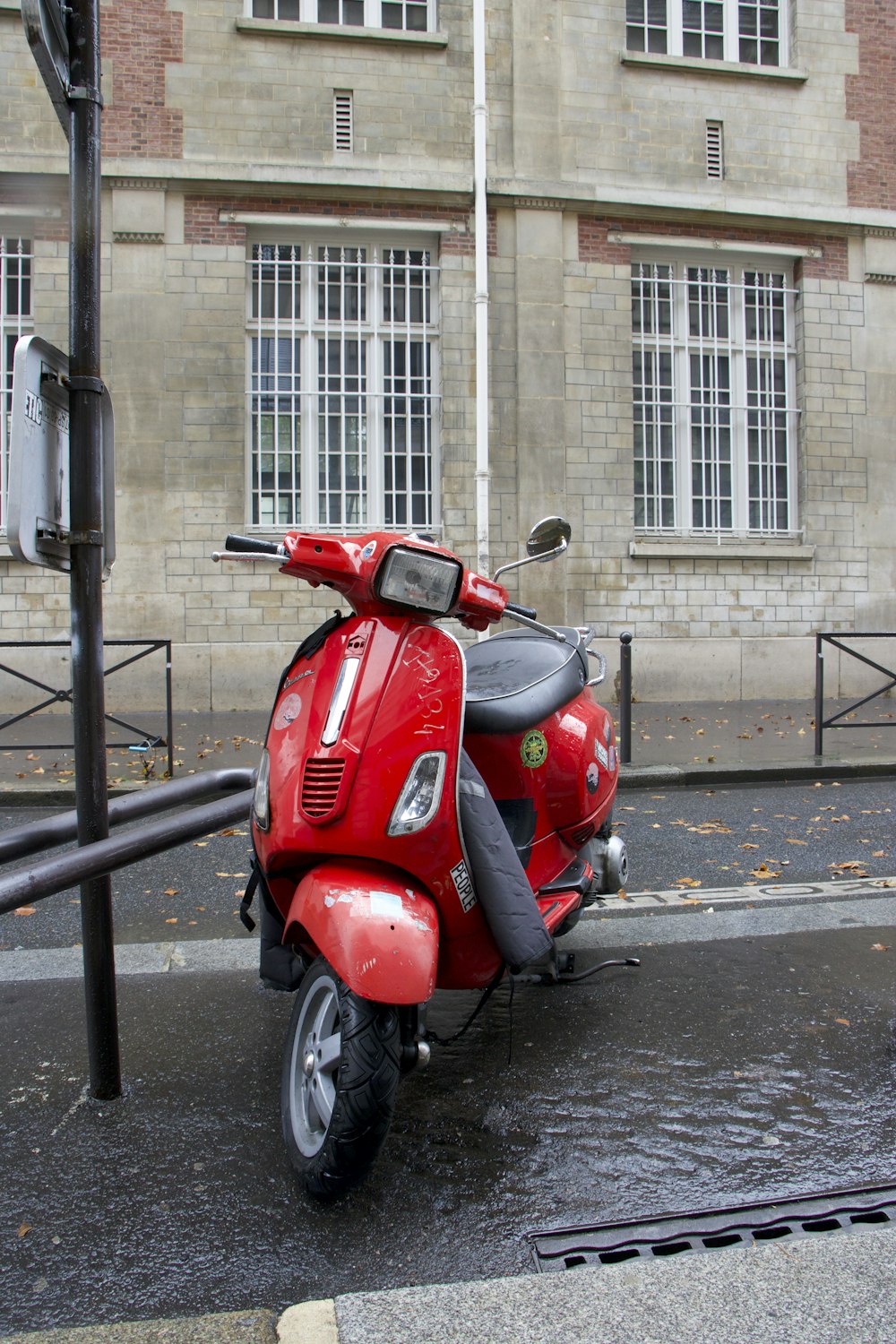 a red scooter parked on the side of a street