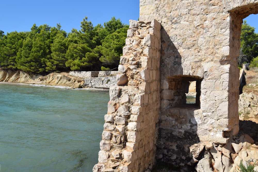 Un edificio de piedra con un lago al fondo