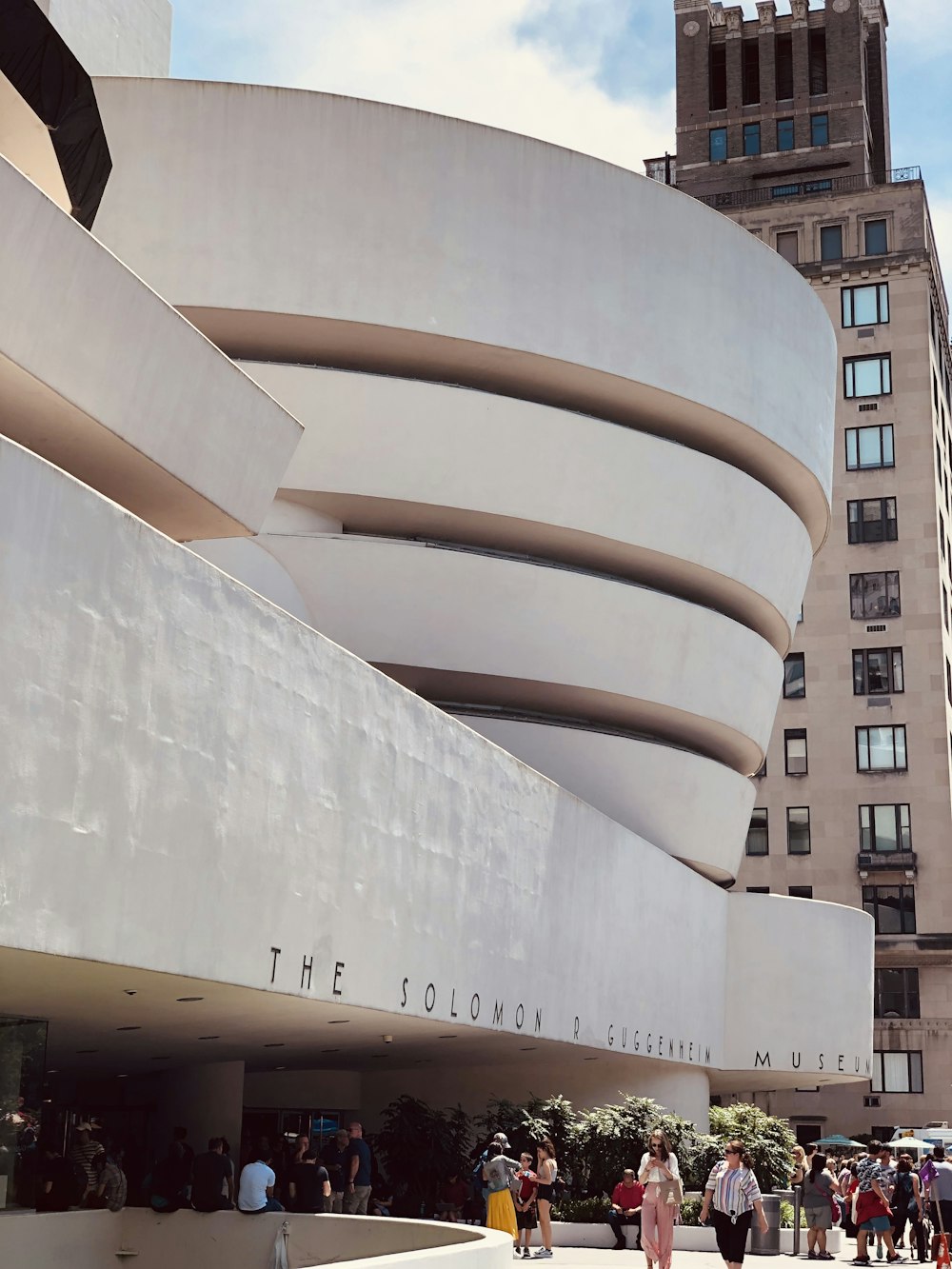 a large white building with a curved roof with Solomon R. Guggenheim Museum in the background