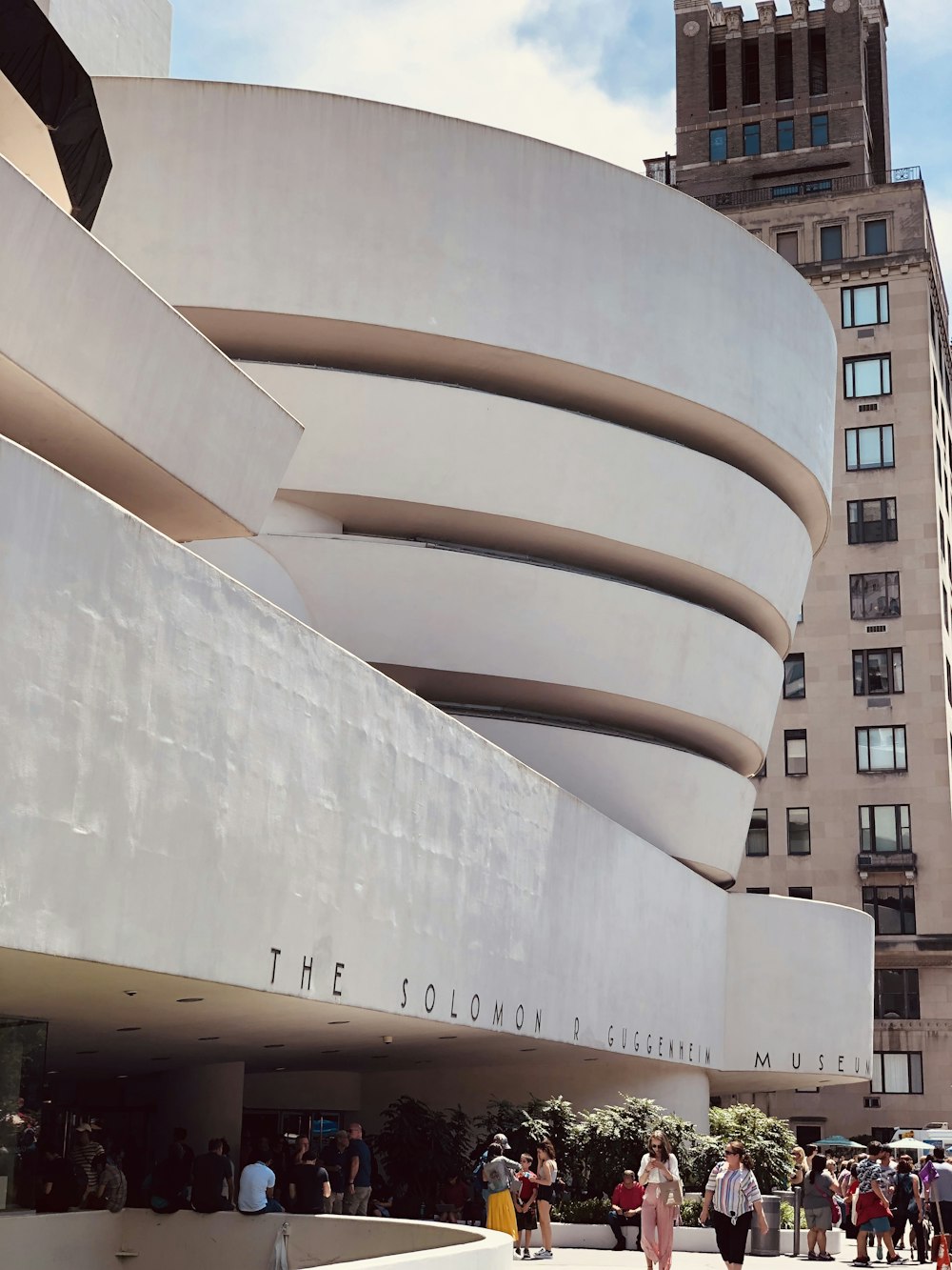 un gran edificio blanco con un techo curvo con el Museo Solomon R. Guggenheim al fondo