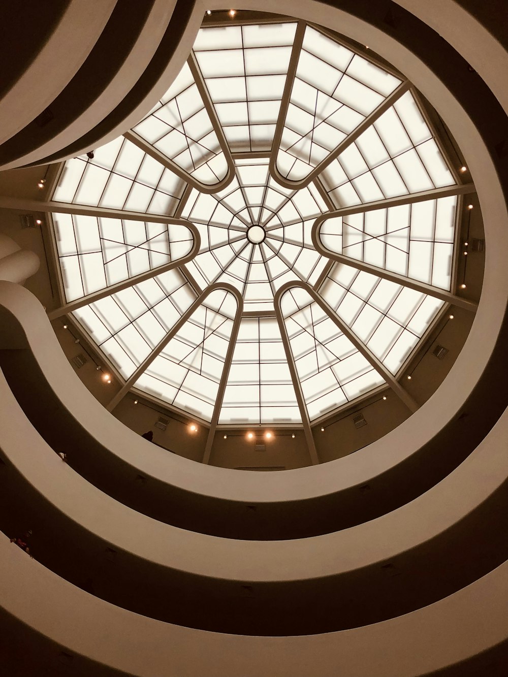 uma escada em espiral com um teto de vidro com o Museu Solomon R. Guggenheim ao fundo